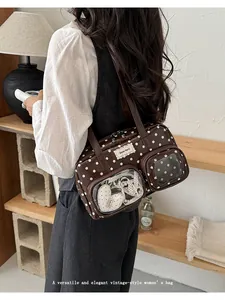 Model wearing an elegant vintage brown shoulder bag with white polka dot patterns