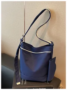 Close-up of navy blue canvas tote bag with white trim on a design book stand