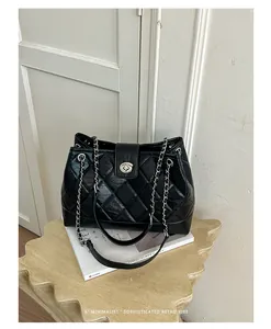 Schicke schwarze Stepptasche mit silberner Kette und Drehverschluss auf Retro-Steintisch