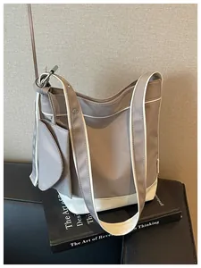 Detail view of a grey and white canvas tote bag with a matching mini pouch on a black book.