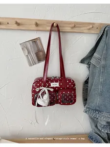 Detailed view of a vintage-style red polka dot shoulder bag hanging on a wooden rack
