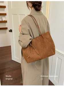 Close-up of a large vintage brown suede tote bag carried on a shoulder