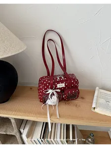 Close-up detail of a vintage red polka dot underarm bag with a pearl bow charm