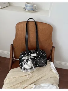 Close-up of black and white polka-dot shoulder bag with heart charm on a wooden chair