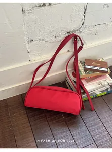 Detail view of a vibrant red nylon retro shoulder bag in a lifestyle setting