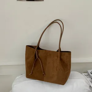Close-up of vintage brown suede tote bag featuring elegant knotted tassel detail