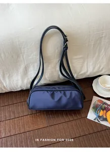 Detail view of a minimalist navy blue retro nylon shoulder bag in a lifestyle setting
