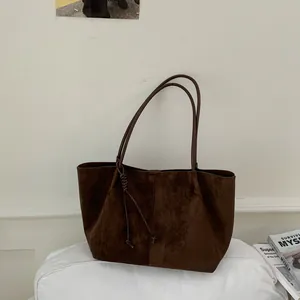 Close-up of a brown suede tote bag with minimalist design and long shoulder straps