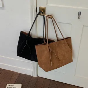 Macro view of minimalist black and brown suede tote bags hanging on a door handle