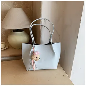 Elegant light blue leather tote bag with cute plush bear charm for stylish women's fashion