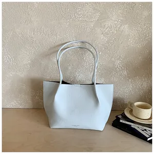 Detailed view of a light blue minimalist tote bag on a wooden table with books