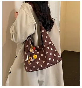 Detailed side view of a vintage brown polka dot suede tote bag with a colorful charm
