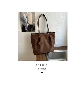 Détail d'un sac cabas en nylon marron avec un accessoire décoratif en forme de cœur