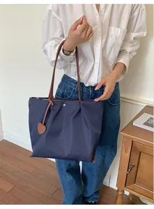 Détail du sac cabas en nylon bleu marine porté par un mannequin chic