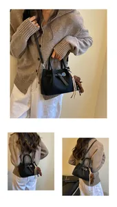 Detailansichten einer hochwertigen schwarzen Eimertasche mit Webstruktur und Bärenanhänger