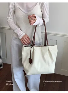 Gros plan d'un sac cabas en nylon blanc avec charm cœur et anses marron