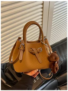 Detailansicht der braunen Handtasche mit Webmuster und niedlichem Teddybären-Anhänger