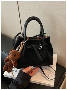 Nahaufnahme einer schwarzen gewebten Beuteltasche mit einem niedlichen braunen Teddybären