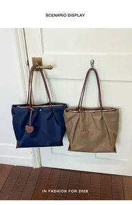 Détail de sacs cabas légers en nylon bleu marine et kaki suspendus à une porte