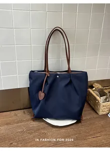 Détail macro d'un sac cabas en nylon bleu marine avec bandoulière en cuir et breloque cœur