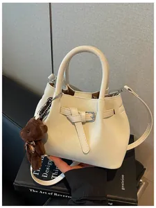 Nahaufnahme einer eleganten cremeweißen Handtasche mit Bärenanhänger