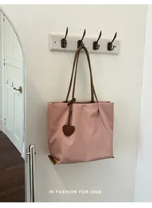 Sac fourre-tout en nylon rose léger avec breloque cœur suspendu à un crochet mural.