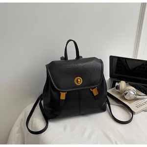 Minimalist black leather backpack with gold hardware displayed next to a laptop