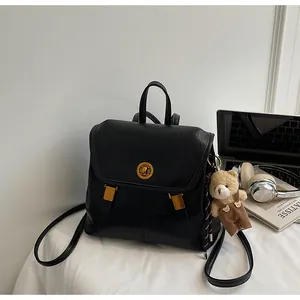 Minimalist black soft leather backpack for women featuring a cute brown teddy bear charm.