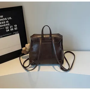 Rear view of a casual brown soft leather backpack for women with a cute plush bear charm