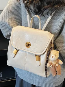 Minimalist creamy white faux leather backpack for women featuring a cute teddy bear charm accessory