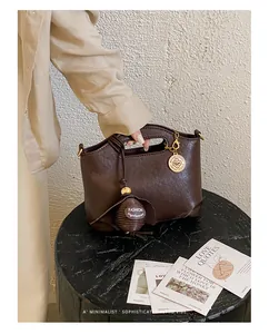 Detailed view of a dark brown minimalist faux leather handbag placed on a black pedestal