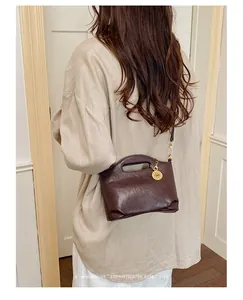 Close-up detail of a sophisticated retro brown crossbody bag worn with a linen shirt