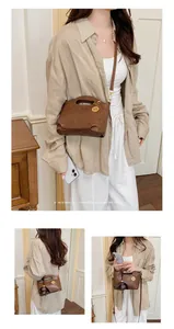 Model wearing a brown retro crossbody bag with a minimalist design and gold charm.