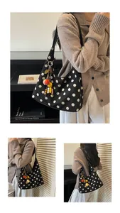 Detail of black suede tote bag with white polka dots and a colorful beaded tassel charm