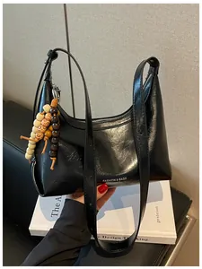 Glänzende schwarze Unterarmtasche mit stilvollem Perlenanhänger und eleganter Form