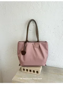 Vue détaillée du sac cabas en nylon rose léger avec lanières brunes et breloque cœur