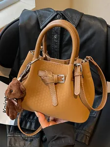 Elegante braune Eimertasche mit einer geprägten Webstruktur und süßem Bärenanhänger