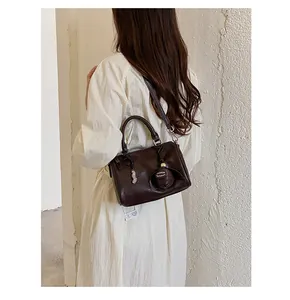 Vue de dos d'un modèle portant un sac Boston vintage marron foncé avec un charme
