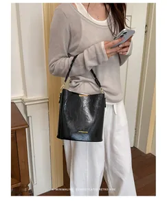 Sophisticated black faux leather bucket bag shown in a lifestyle indoor setting