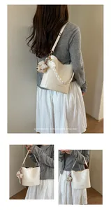 Detail of cream bucket bag with braided handle and cute teddy charm accessory