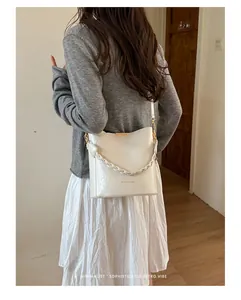 Back view of a chic cream bucket bag with a stylish braided handle worn by a model