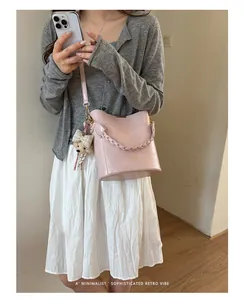 Minimalist pink bucket bag with bear charm shown in a lifestyle street style outfit
