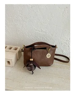 Detail of minimalist brown retro crossbody bag with decorative leaf charm