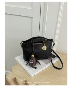 Minimalist black crossbody bag with gold hardware and tassel detail on a magazine