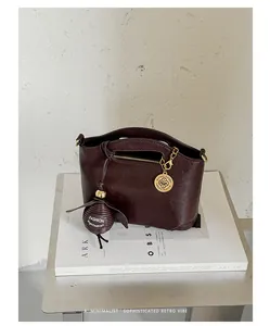 Detailed view of a dark brown retro handbag with golden hardware on a white book