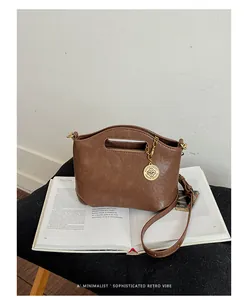 Close-up detailed view of a brown minimalist retro handbag resting on an open magazine