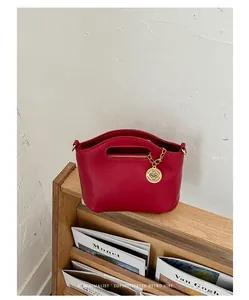 Detailed macro shot of a minimalist red handbag displayed on a wooden book shelf