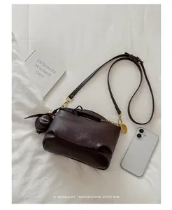 Detailed view of a retro brown leather crossbody bag with elegant gold hardware accessories.