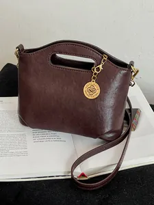 Stylish dark brown faux leather handbag with gold charm and crossbody strap for women.