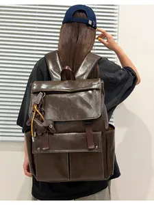 Détail d'un sac à dos en cuir PU marron pour femme avec rabat et breloque chien
